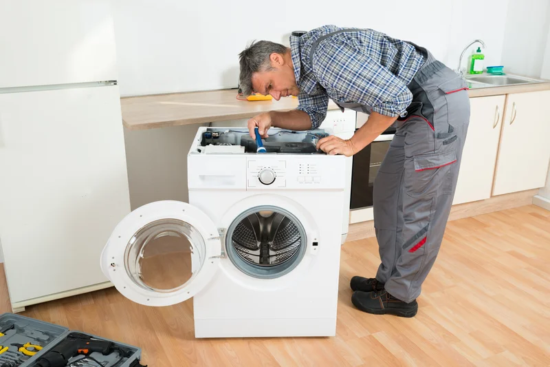 Professional technician repairing front-load washing machine.