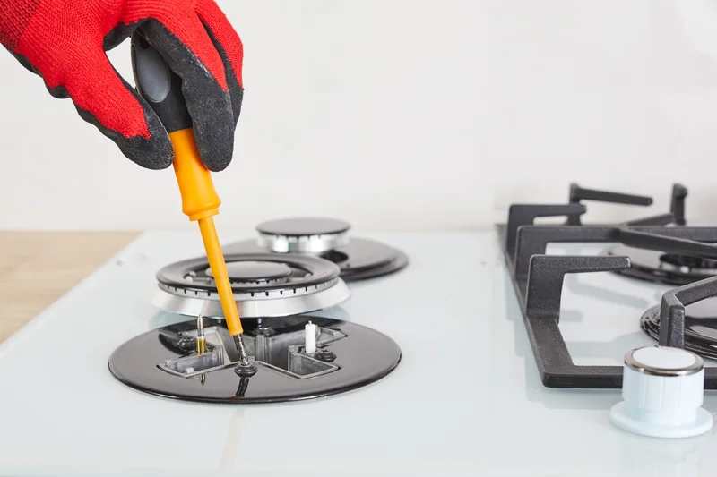 Repairman fixing a modern white gas stove cooktop burner