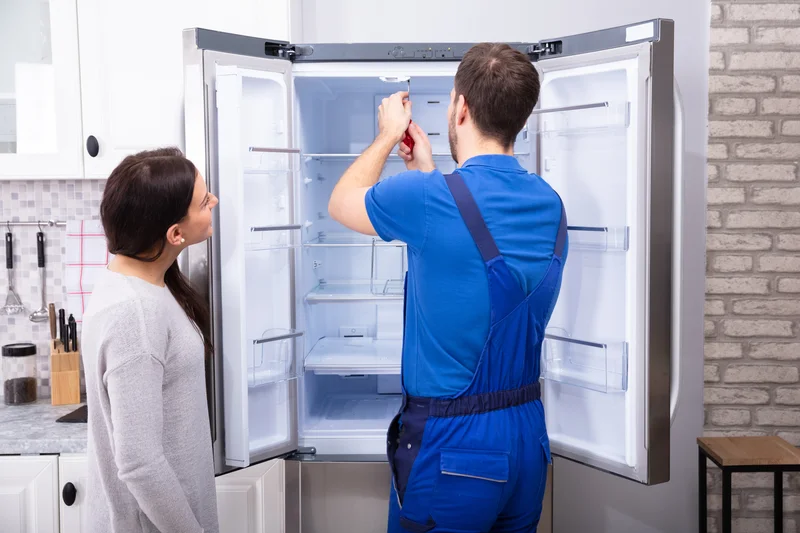 Professional refrigerator repair technician fixing kitchen appliance