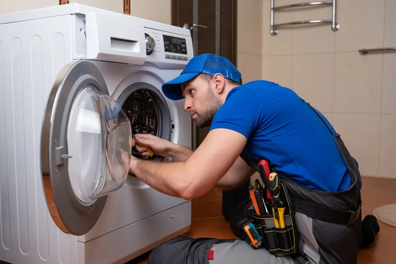 Appliance repair technician servicing a front-load washing machine.