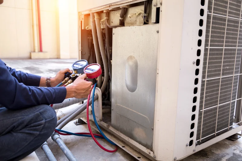 HVAC service technician measuring pressure on outdoor AC unit