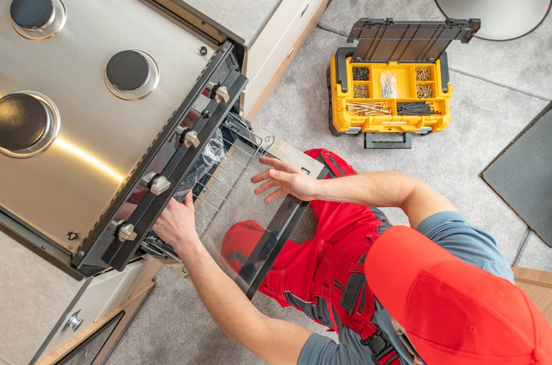 Appliance repair technician fixing a modern stainless steel oven
