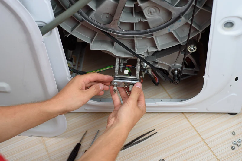 Appliance repairman fixing a broken washing machine heating element